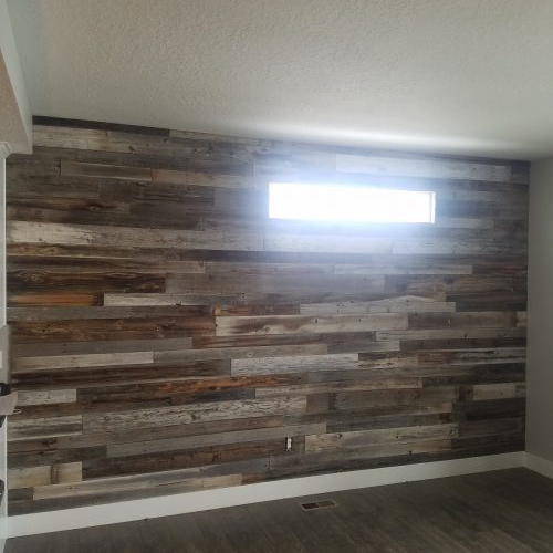 wall transformed with reclaimed wood planks covering the surface, retaining the small horizontal window at the top.