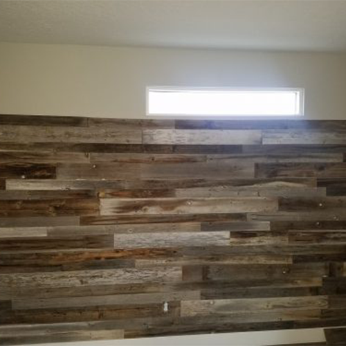 Interior wall covered in reclaimed wood planks of varying shades and textures, with a small horizontal window above the wall letting in natural light.