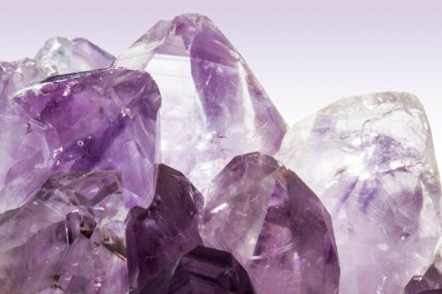 Close-up of several purple and clear amethyst crystal points with a smooth gradient background, reminiscent of the natural beauty often found in homes in Utah, showcasing their transparent and faceted surfaces.