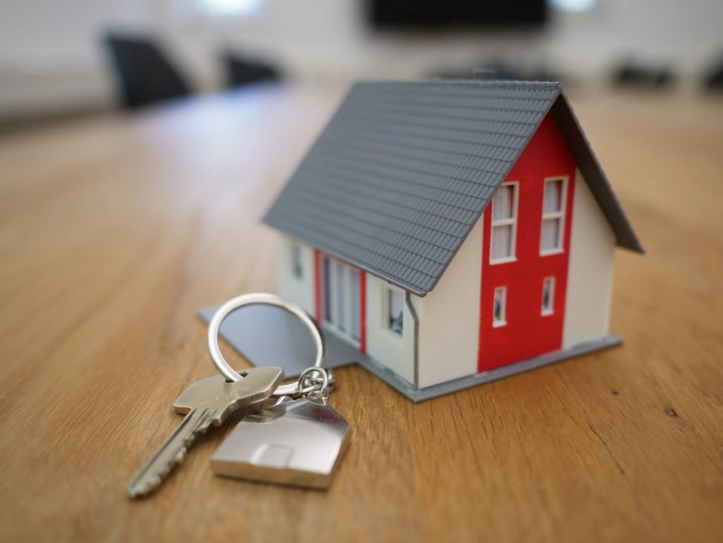 A tiny white and red home replica next to house keys