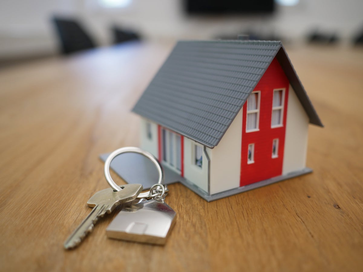 A tiny white and red home replica next to house keys