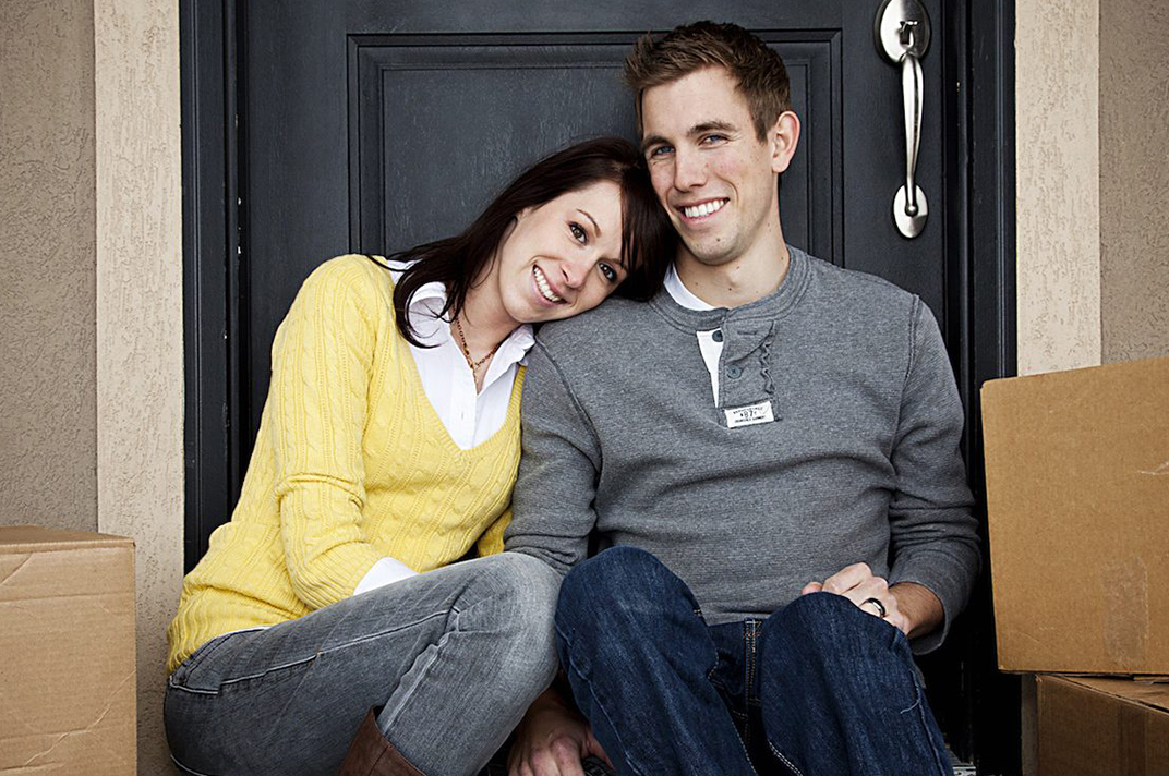 two people sitting on the front steps with moving boxes