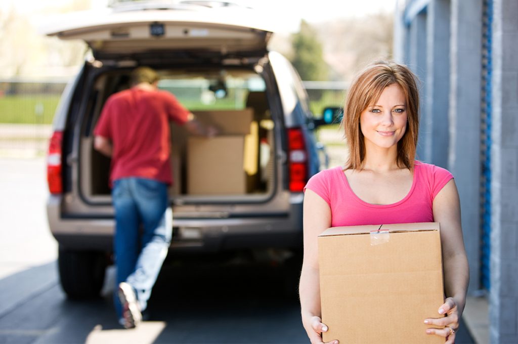 Two people unpacking boxes from a car for a new home.