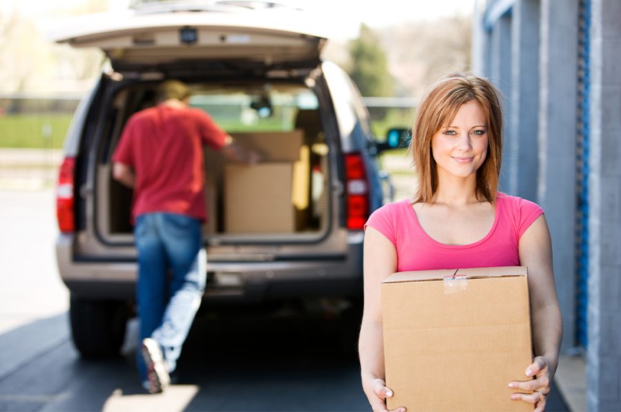Two people unpacking boxes from a car for a new home.