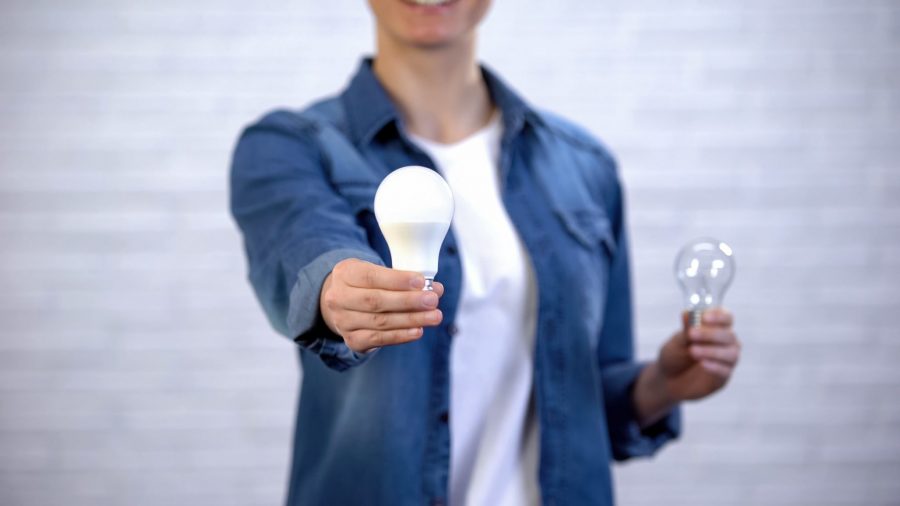 Woman Holding An LED Bulb in Home Hand and An Incandescent in The Other