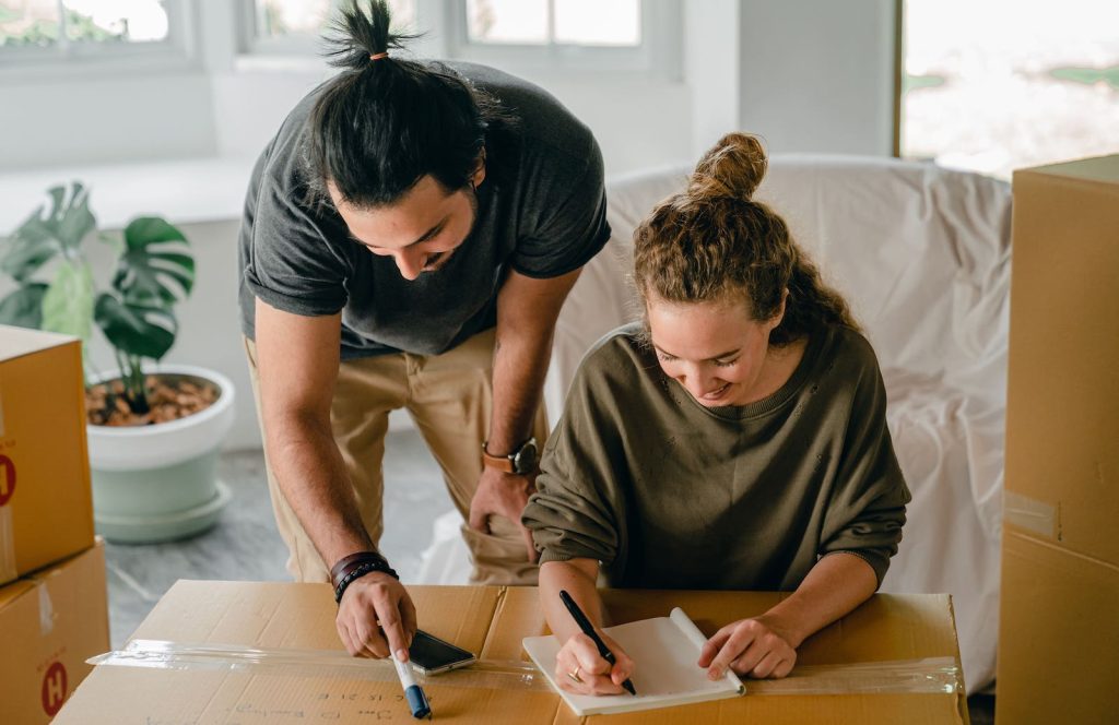 A Couple Writing Contents on a Moving Box