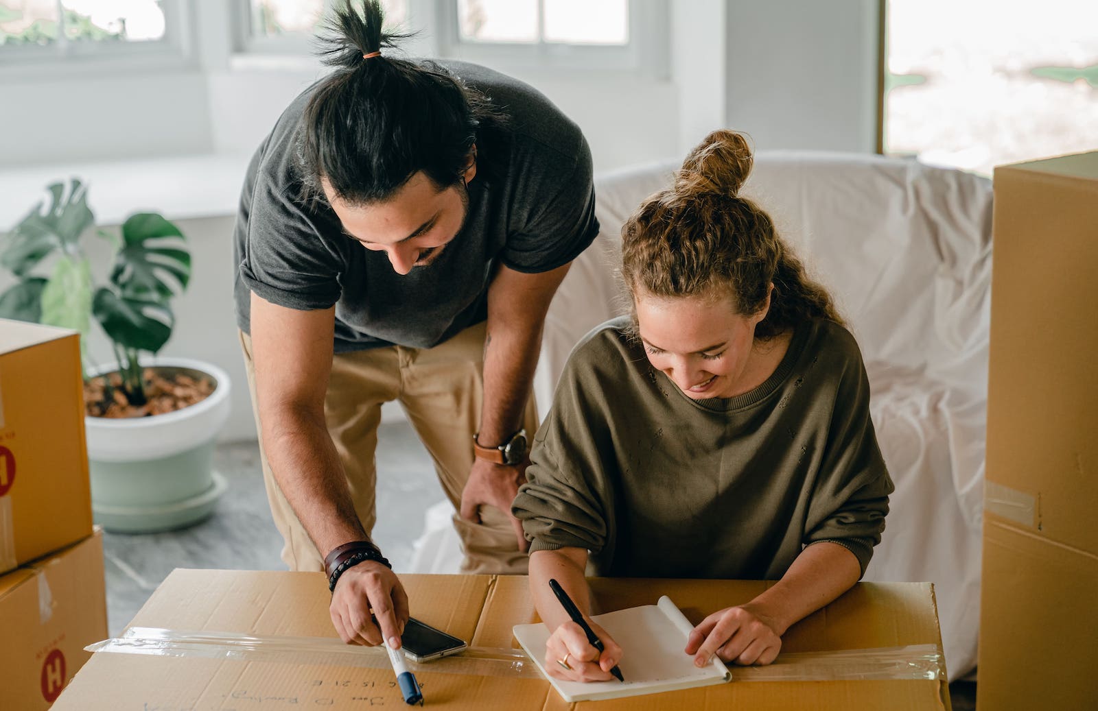 A Couple Writing Contents on a Moving Box