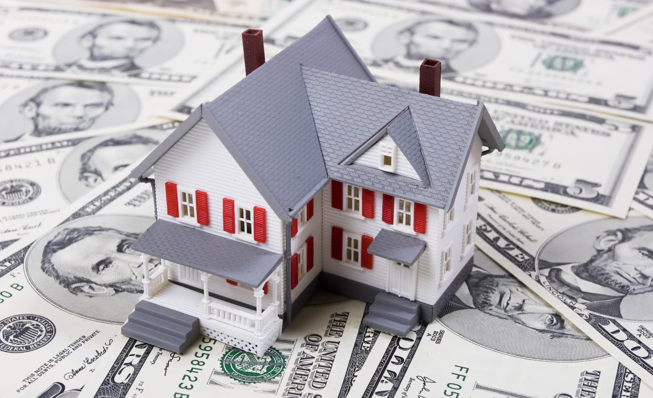 New Homes Toy Model On Top Of Five Dollar Bills