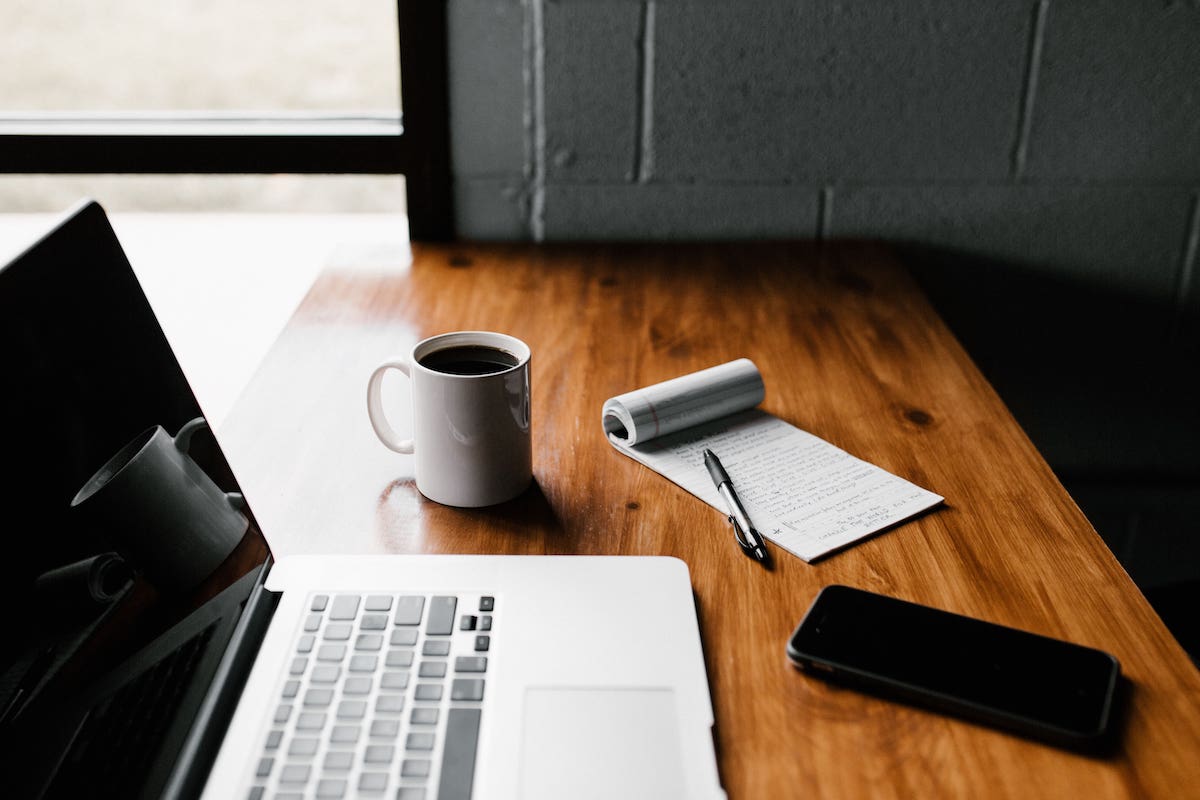 Laptop, A Phone, A Cup of Coffee, A Notepad and Pen In A New Home From McArthur Homes
