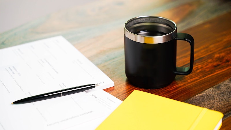 Printed Paperwork Next to a Cup of Coffee