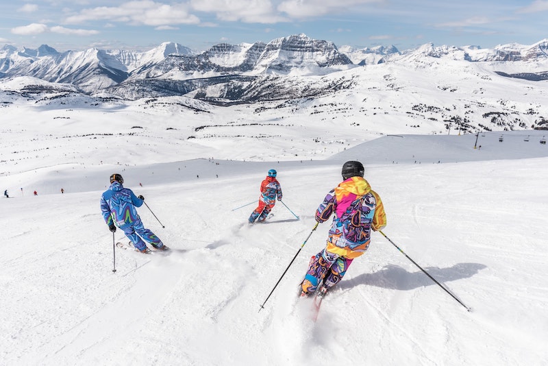2 people in yellow jacket and blue helmet skiing on snow covered mountain in Utah