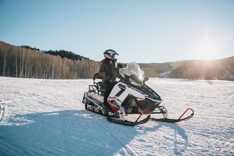 person riding on white and black snowmobile in the winter in Utah