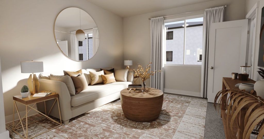 Modern living room with neutral tones, featuring a beige sofa with decorative pillows, a round wooden coffee table, a large round wall mirror, and a patterned area rug, with natural light streaming through a window with white curtains.
