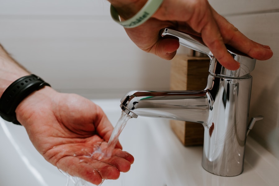 Person Washing Their Hands Under Faucet