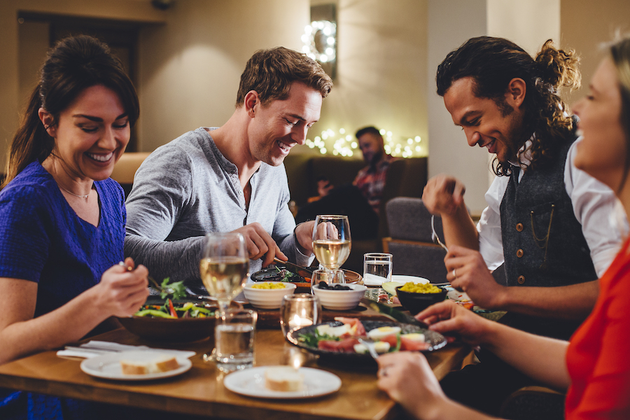 Group of friends enjoying an evening meal with wine.