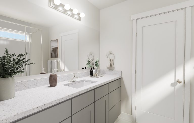 A modern bathroom found in many homes in Utah, featuring light gray drawers, a white countertop, a large mirror, decorative plants, soap dispensers, towel rings, and a closed white door. Bright lighting shines above the mirror.