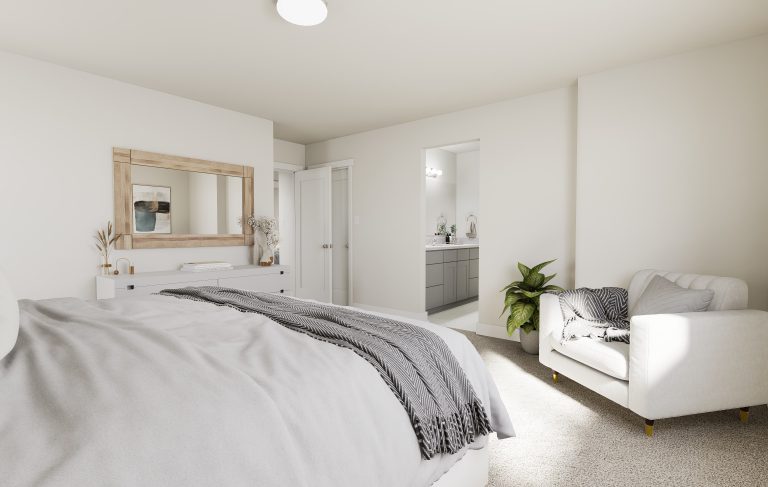 A bright, modern bedroom in homes in Utah features a large bed, a white armchair with a throw blanket, a dresser with mirror, and an open doorway leading to a bathroom with gray cabinets and a potted plant nearby.