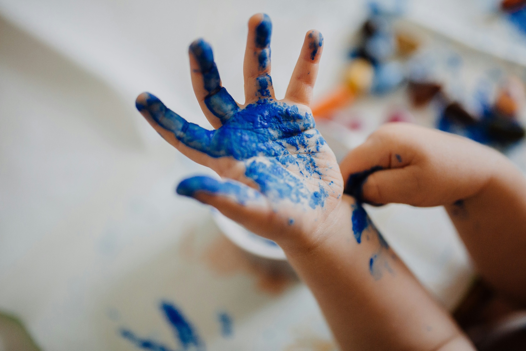 Child with blue paint on hand