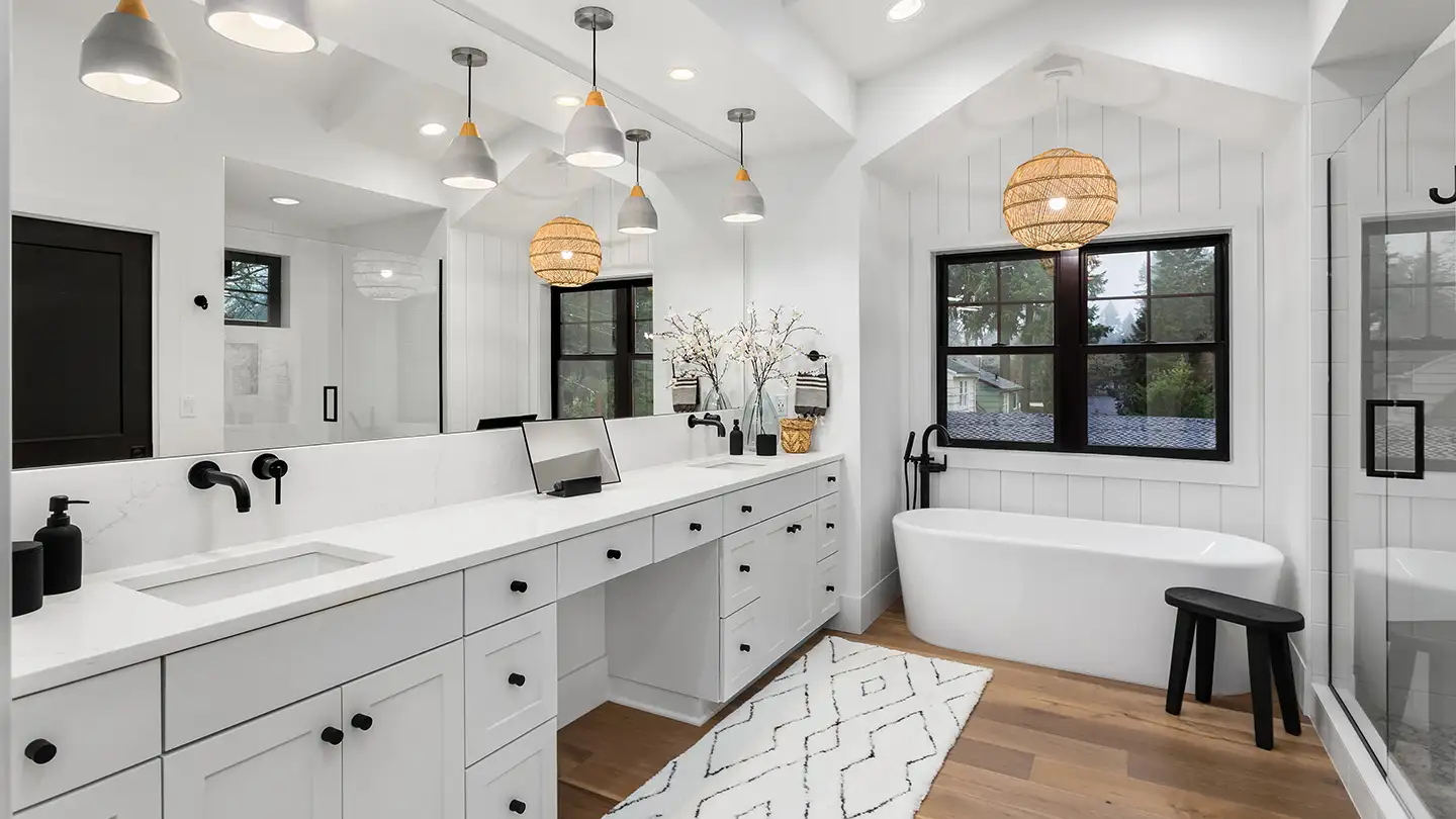 Modern white bathroom with double-sink vanity, large mirror, pendant lights, a freestanding tub, and rattan globe fixture.