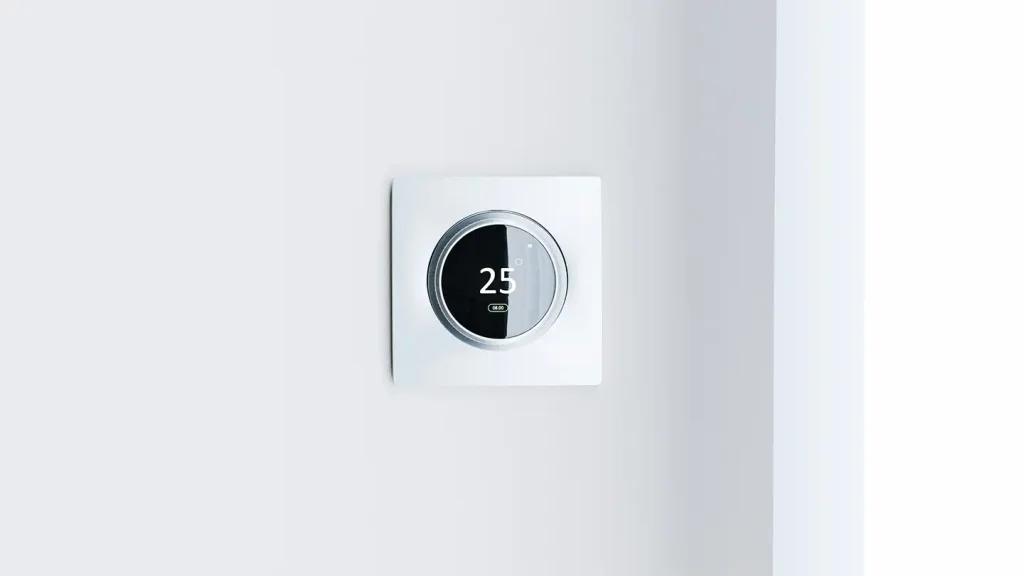 Round smart thermostat mounted on a white wall displaying 25 degrees, an energy-saving feature found in modern new construction homes.