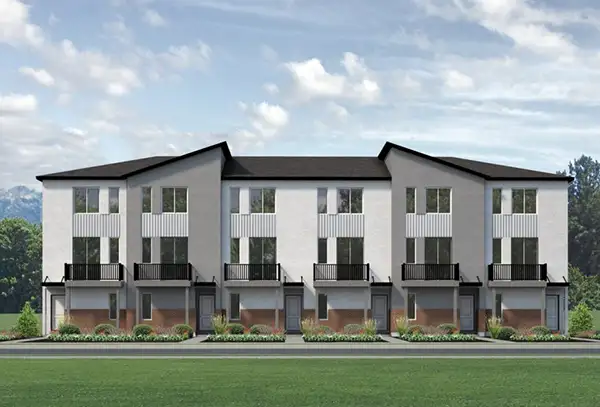 Row of three-story Dawson Place townhomes with white exteriors, dark roofs, and balconies, set against mountains and a green lawn.