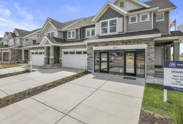 Harvest Park craftsman-style townhomes with stone and gray siding, attached garages, and a model home sales office along a paved driveway.