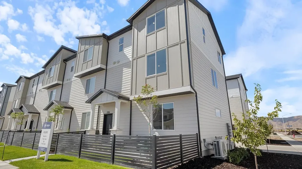 Three-story townhomes with gray board-and-batten siding and a dark slat fence at Arrowhead Ranch in Payson, Utah