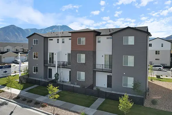 Three-story townhomes at Arrowhead Ranch with gray, white, and wood-tone siding and mountains behind