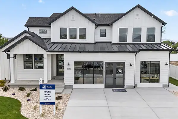 White two-story model home at Pierson Farms with black trim and a sales office sign out front