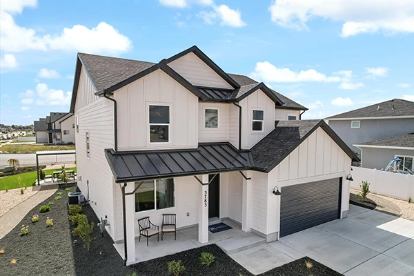 Two-story modern farmhouse with white board-and-batten siding, black metal roof accents, covered porch, and attached two-car garage.