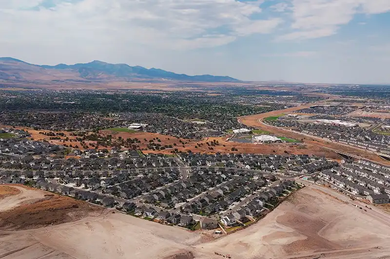 Aerial view of an established neighborhood with a school and sports fields, mountains in the distance